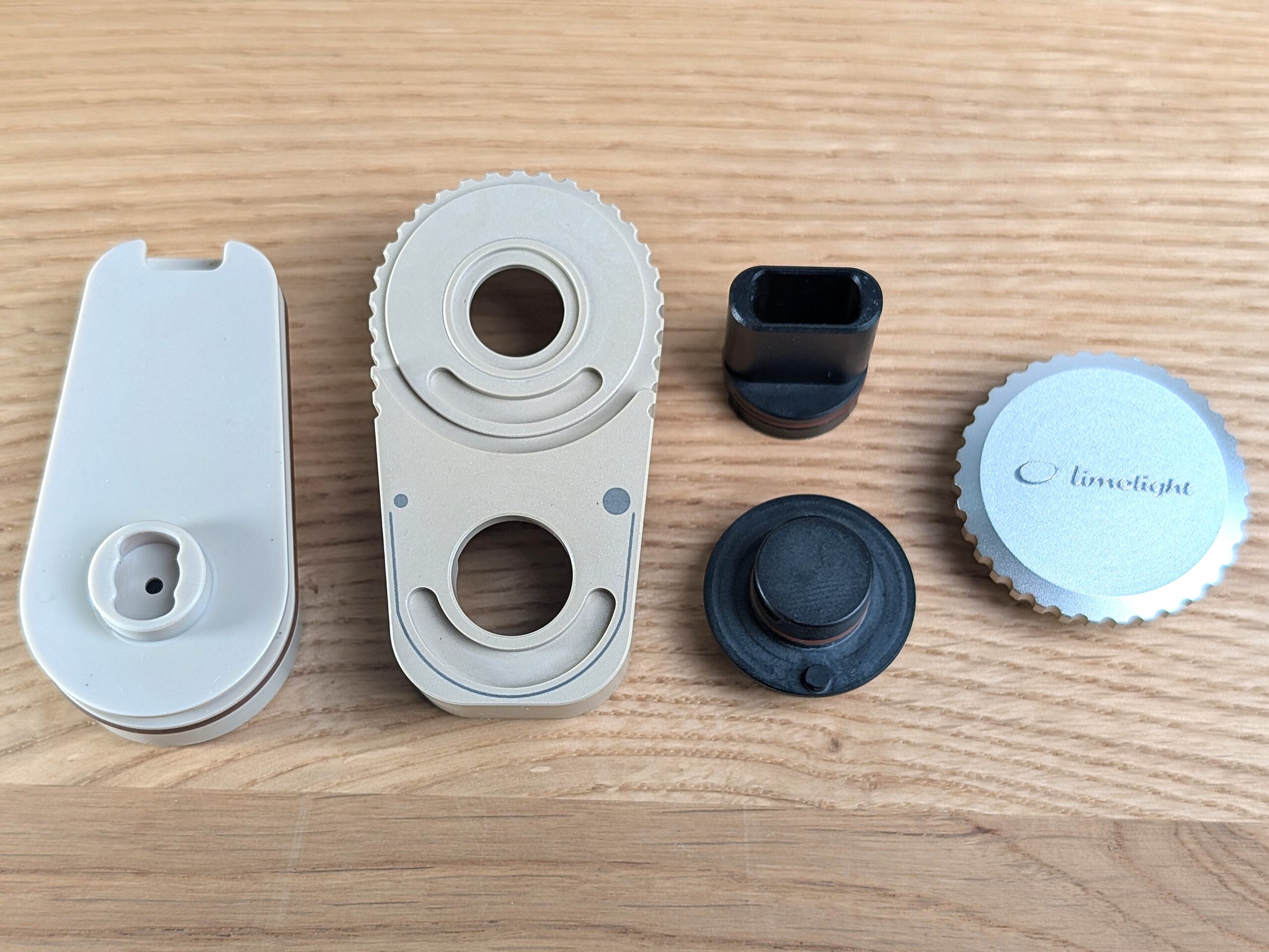 Die vierteilige Kühleinheit des Frolic liegt zerlegt zusammen mit dem Mundstück auf einem Holztisch.