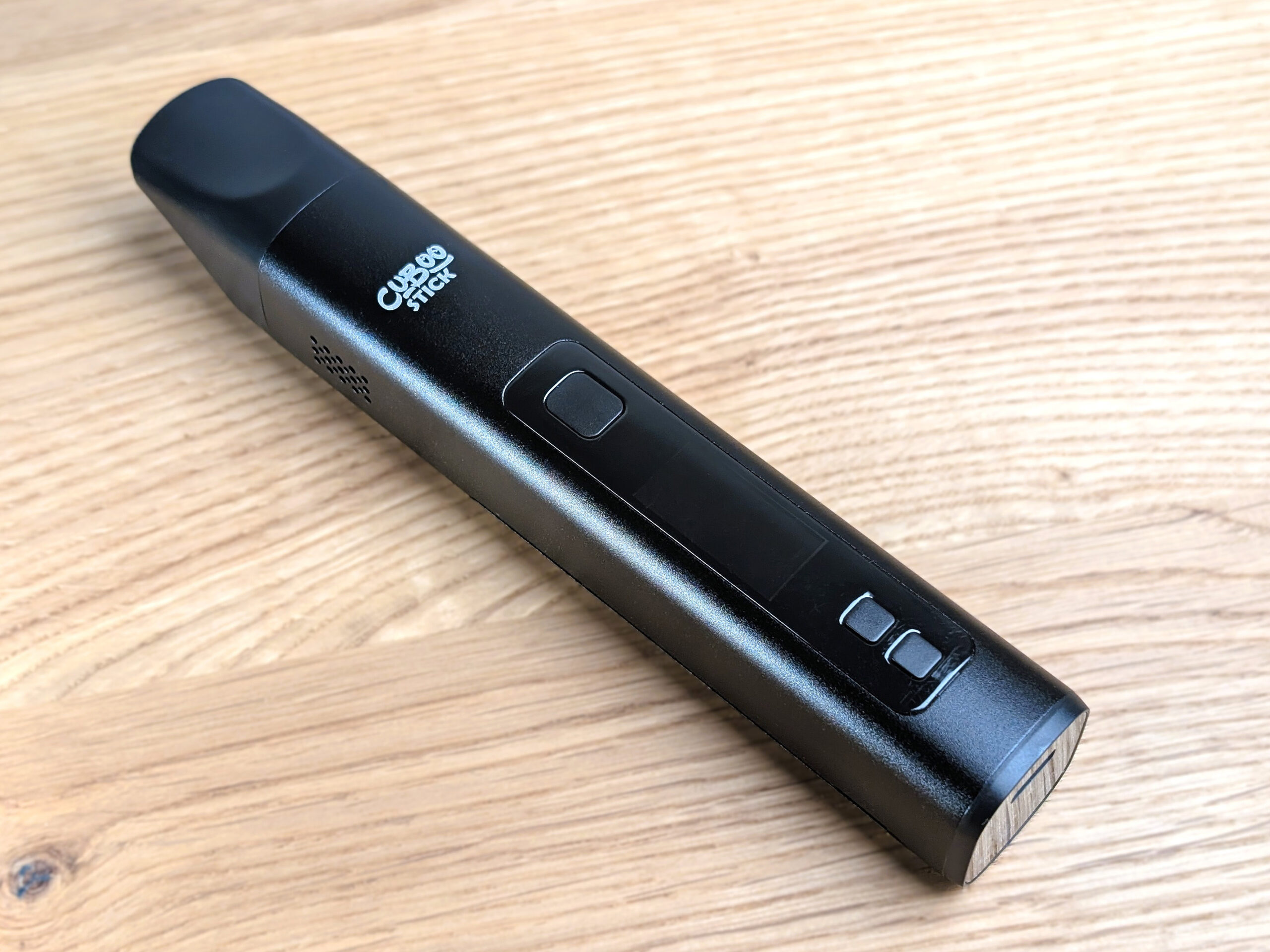 The Cuboo Stick vaporizer lying on a wooden table.