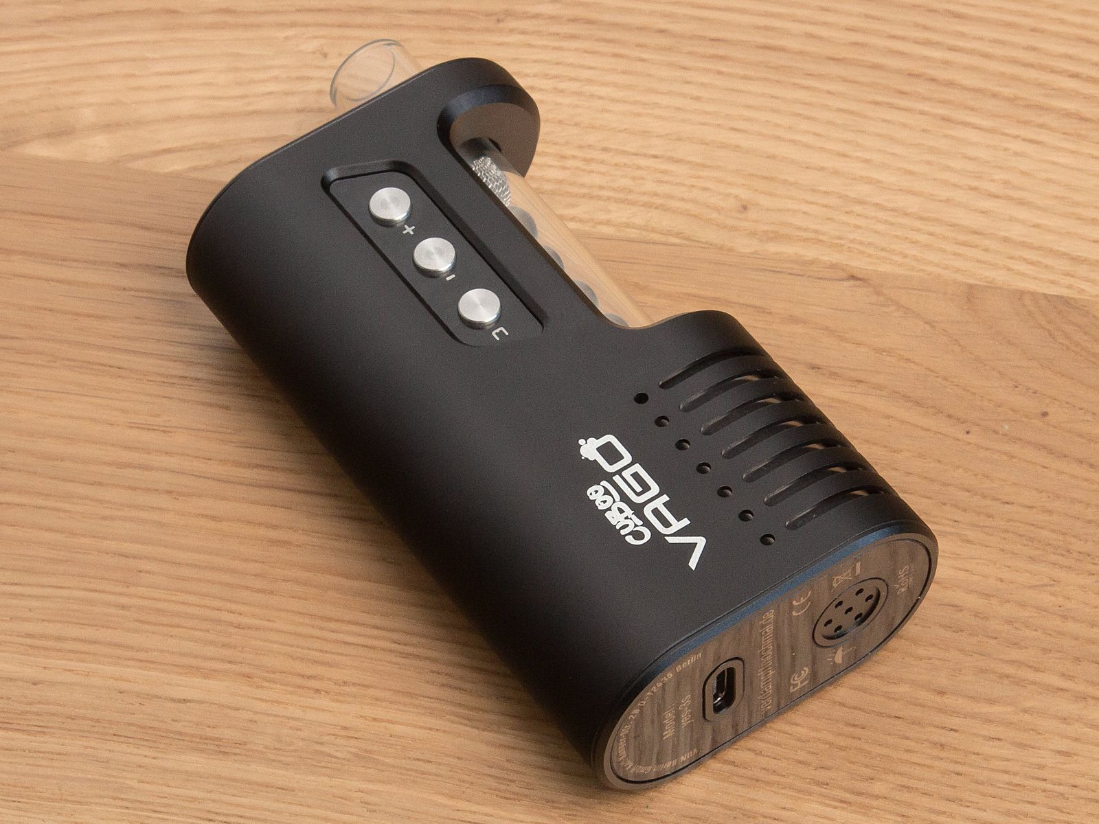 Der Cuboo-Vago-Vaporizer liegt auf einem Holztisch. An der Unterseite sind die USB-C Ladebuchse und der Lufteinlass zu erkennen.