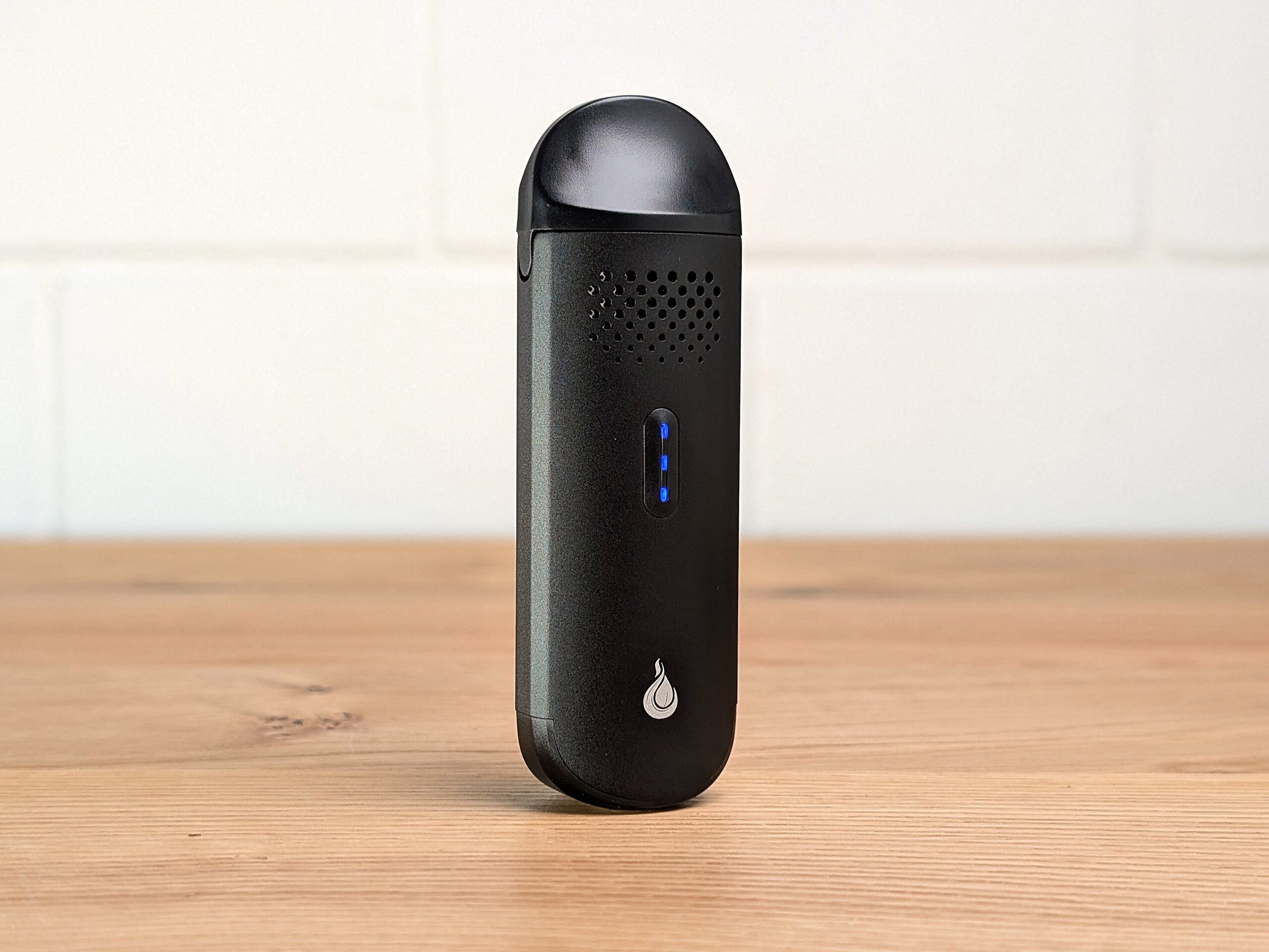 A Flowermate The Cap vaporizer standing on a table with three blue LED lights lit.