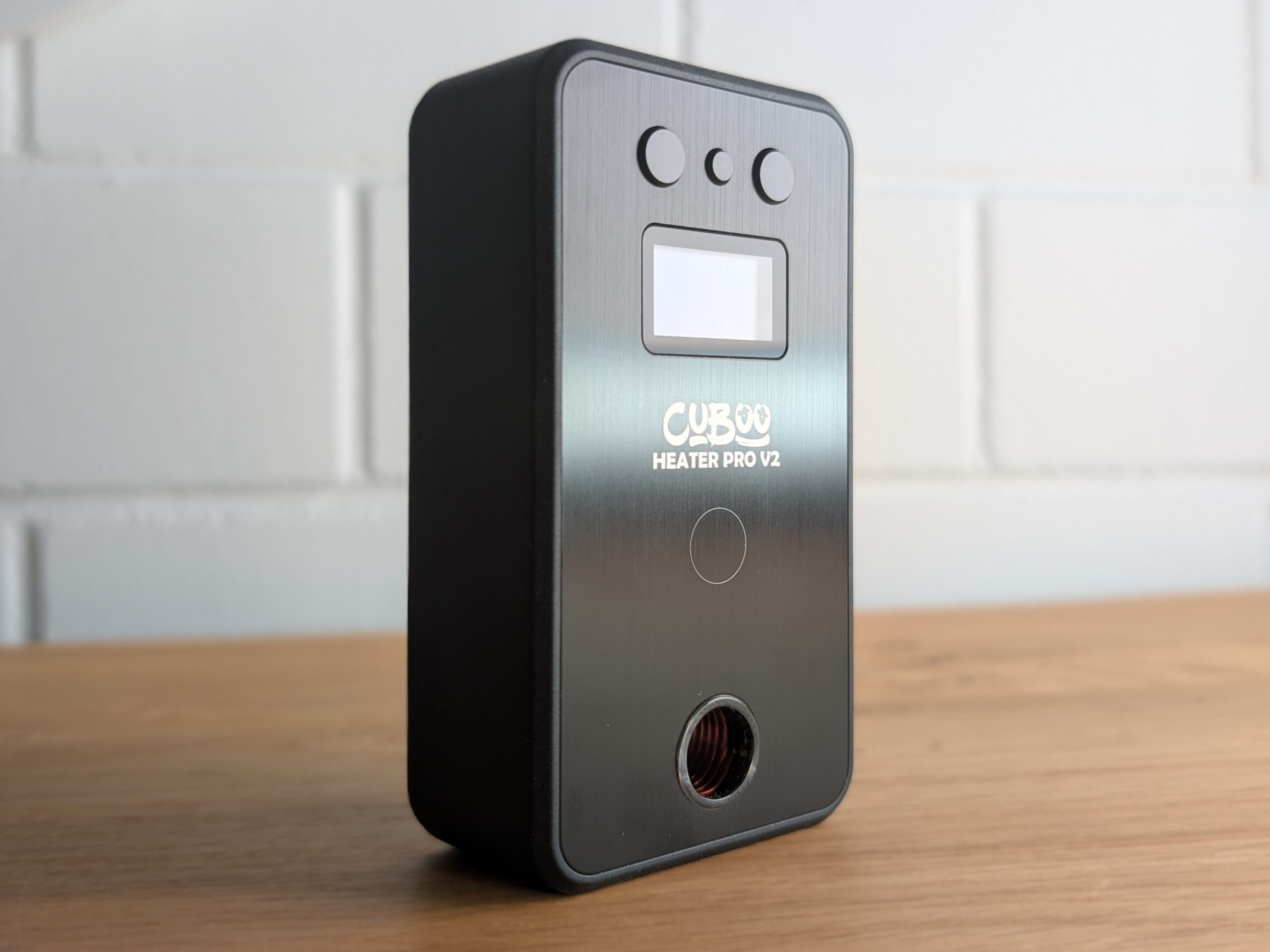 Der Cuboo-Heater steht auf einem Holztisch. Im Hintergrund ist eine unscharfe Backsteinwand zu erkennen.