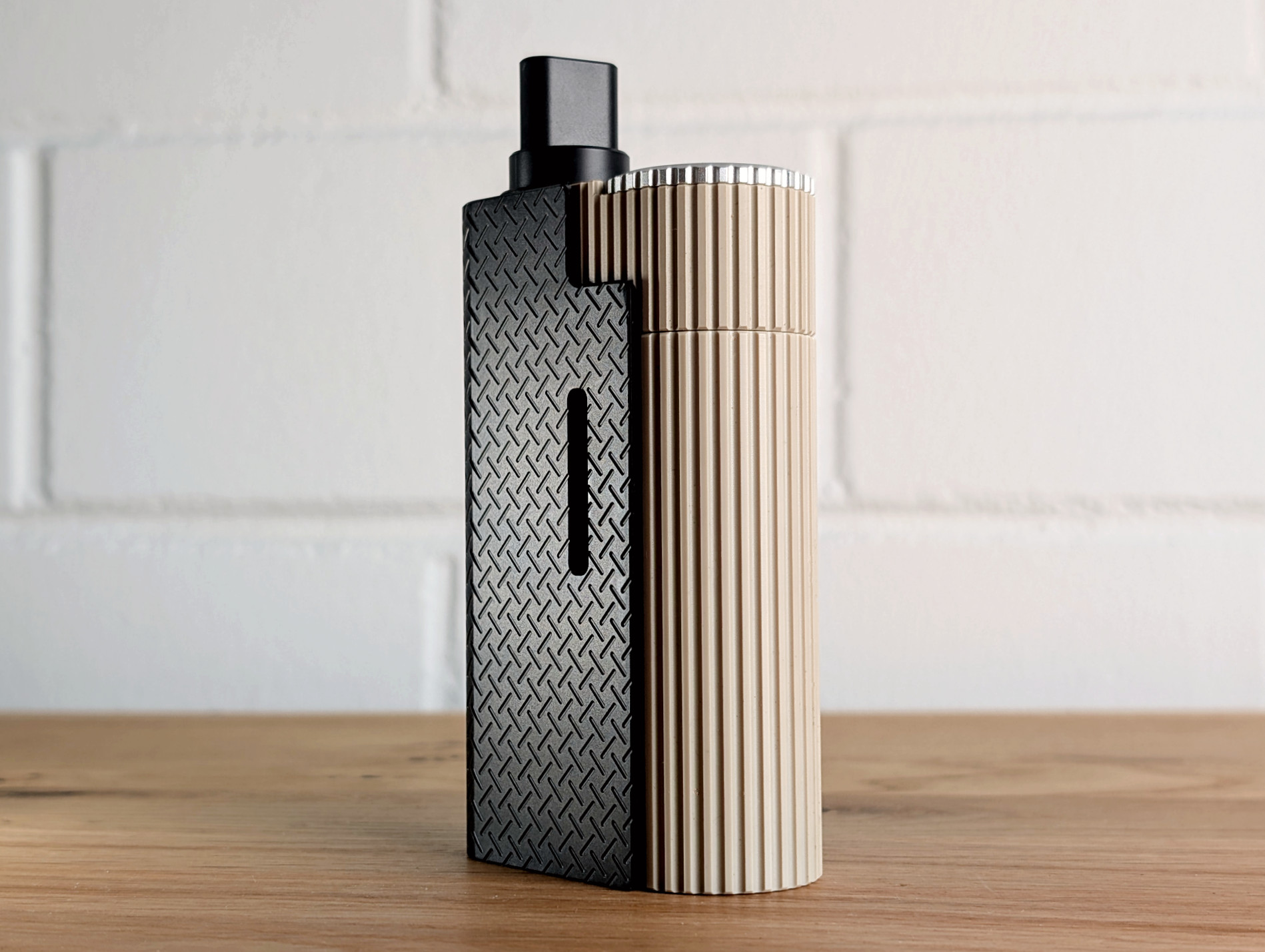 The Frolic Thermal Extractor with its back facing the viewer on a wooden table. A blurred white brick wall is visible in the background.