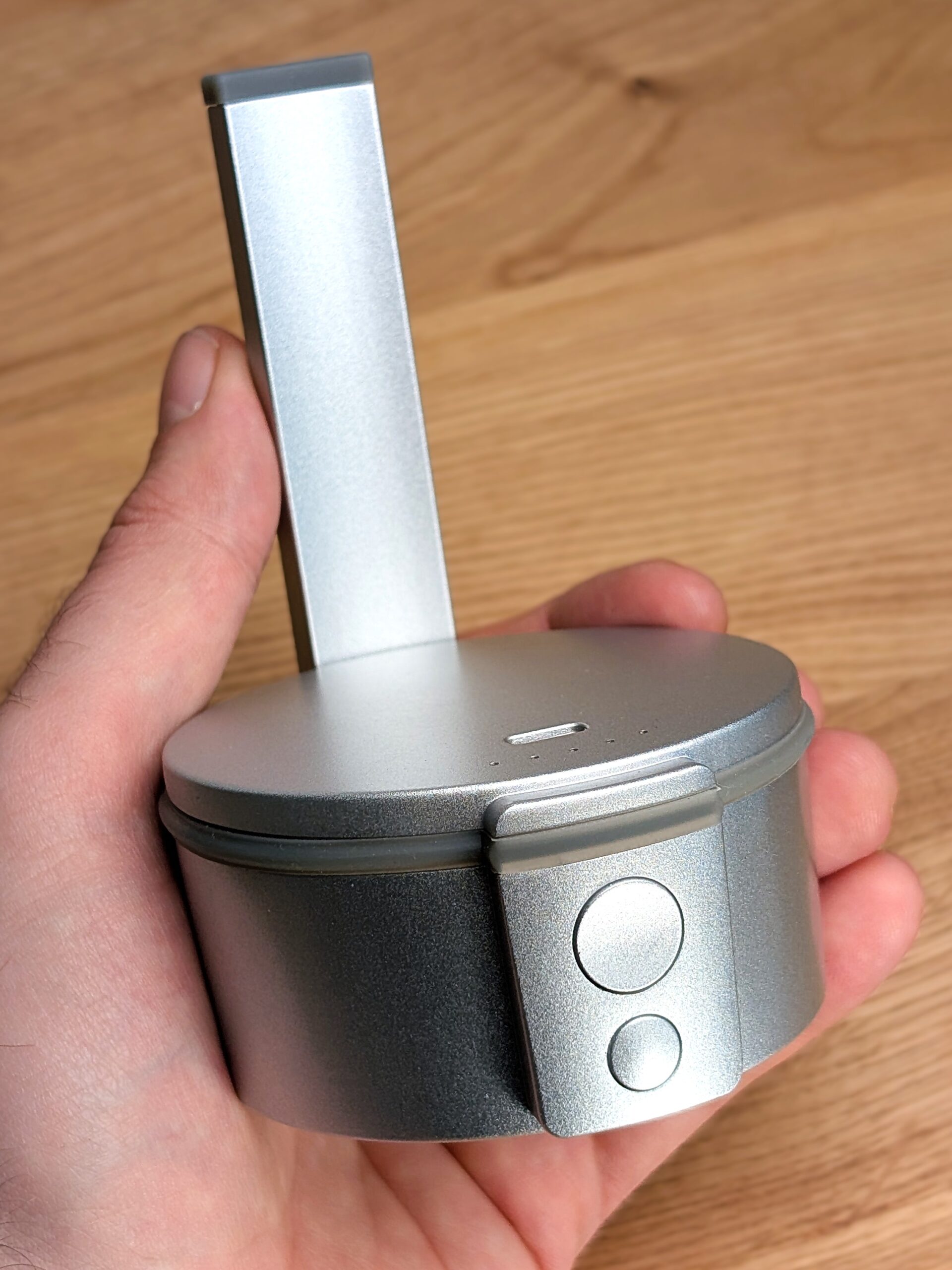A hand holding the Tafée Bowle vaporizer. A blurred wooden table is visible in the background.