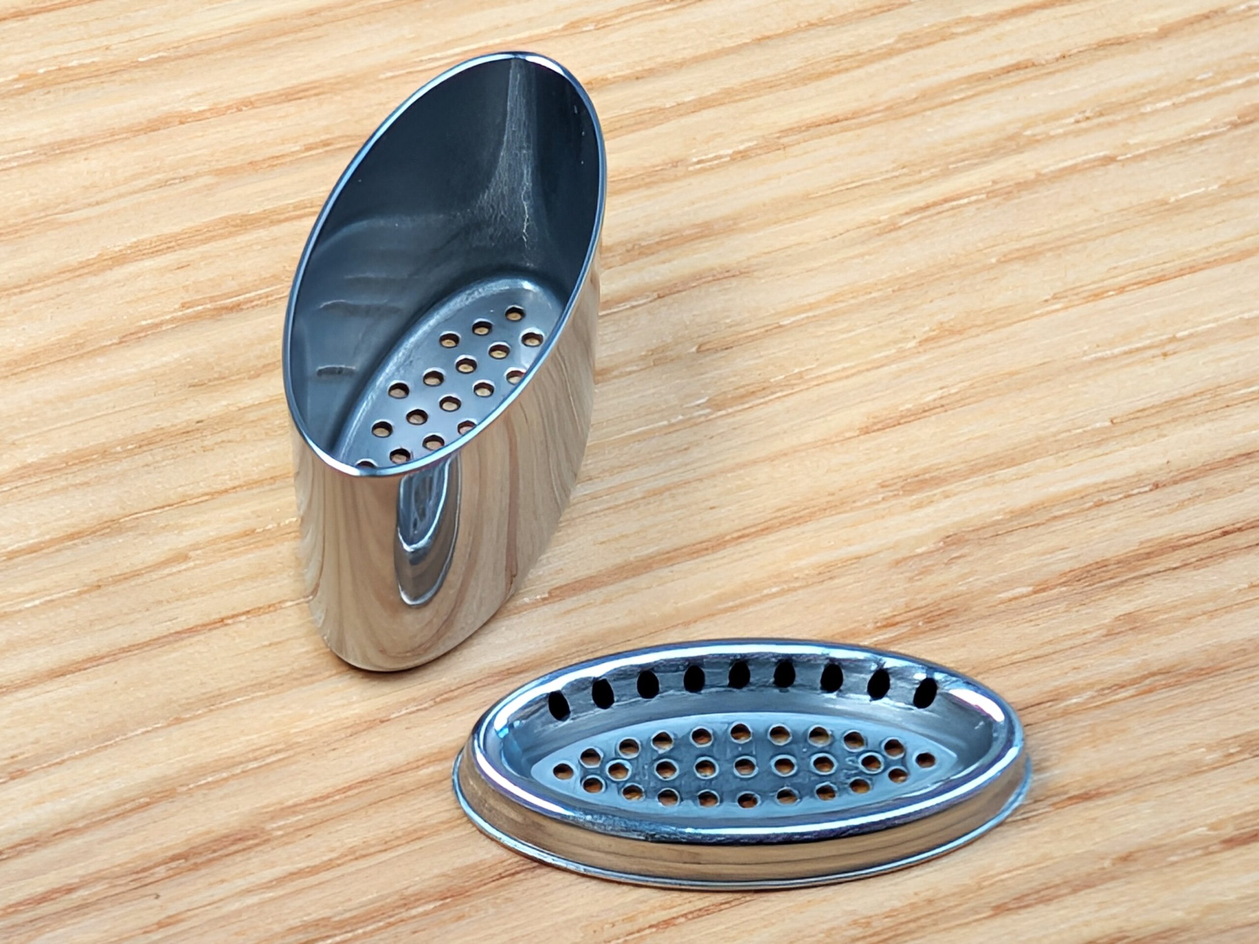 An open herb capsule of the Starry 4 Vaporizer lying on a wooden table. The lid is placed in front on the right.