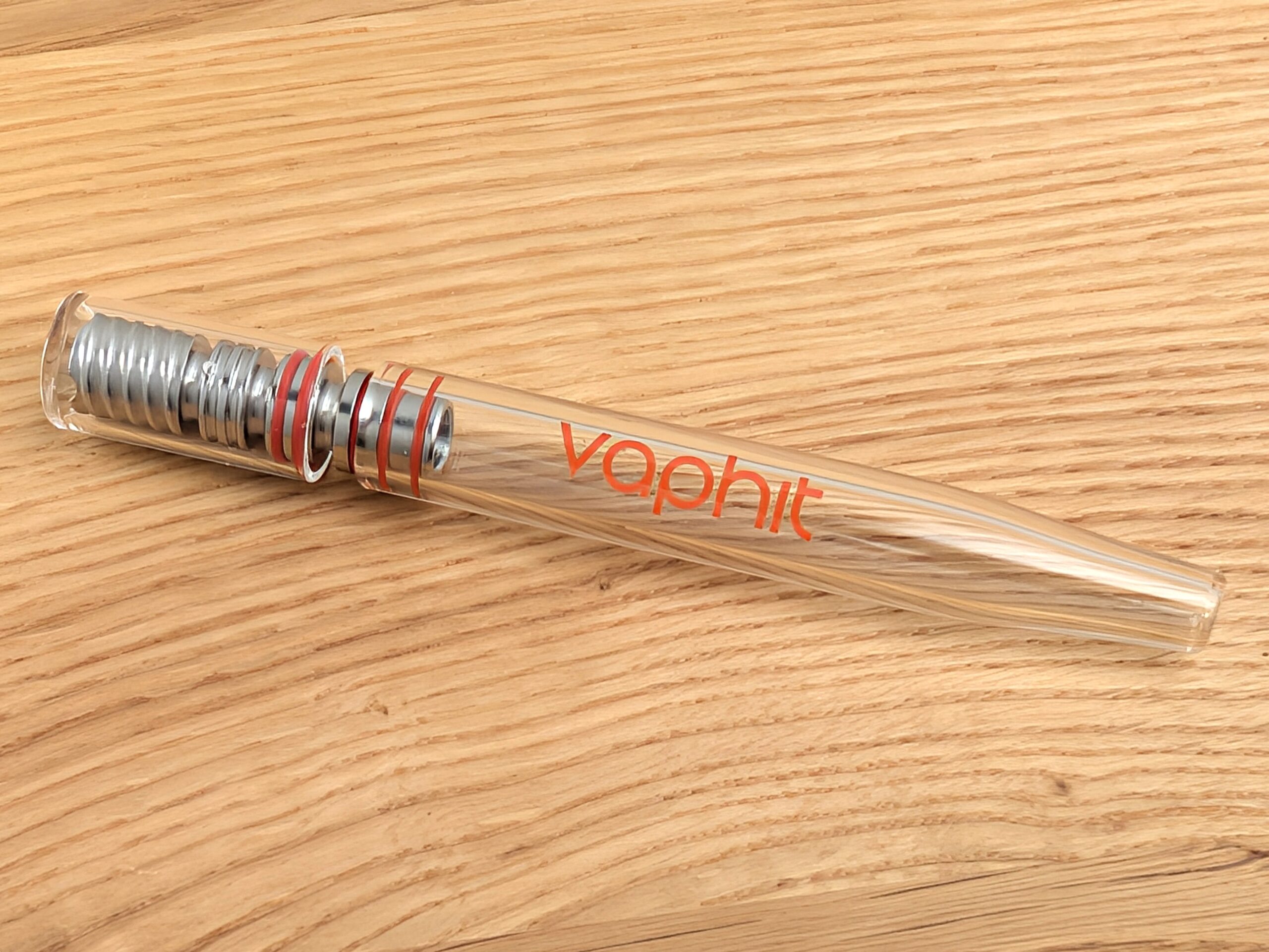 A Vaphit vaporizer lying diagonally on a wooden table.