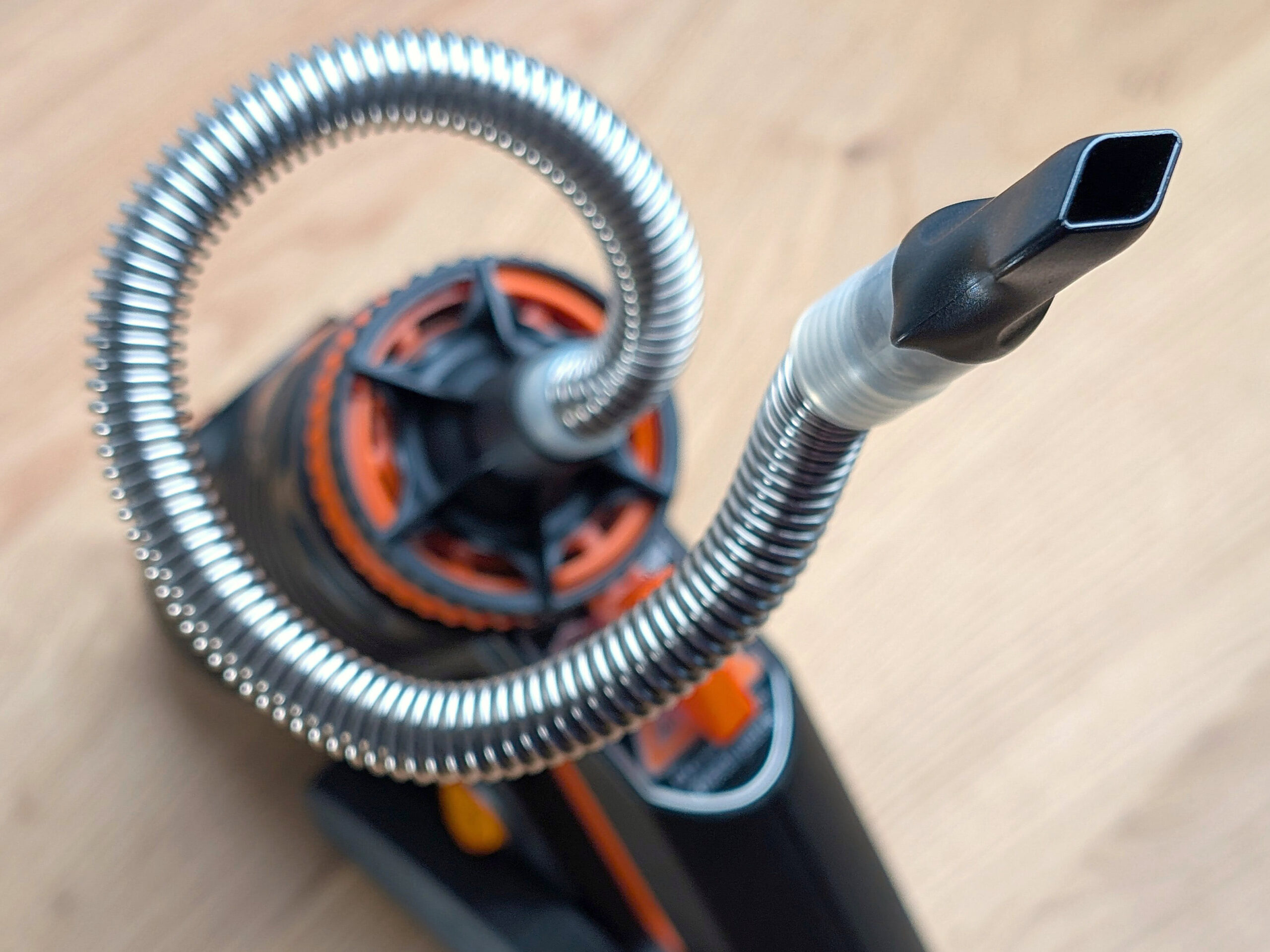 A Plenty vaporizer sits on a wooden table. The perspective is top-down. The mouthpiece points to the upper-right corner of the image.