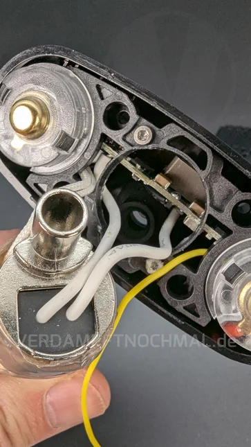 A hand holds the metal airway. The airway is connected to the open Angus Enhanced with two white cables.