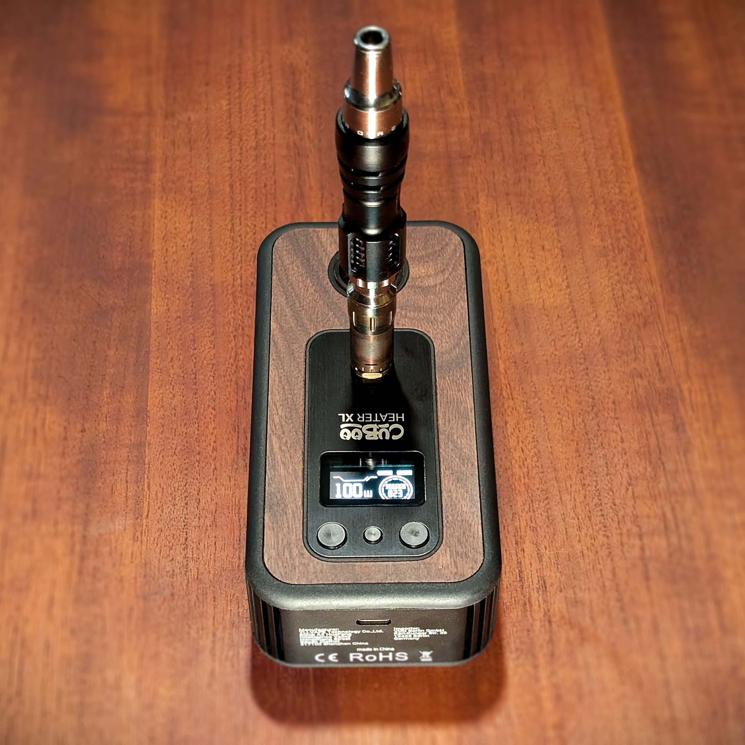 The Cuboo Heater XL is placed on a wooden table. The Mad Heaters Tempest 2 is positioned on the heater's magnetic contact point.