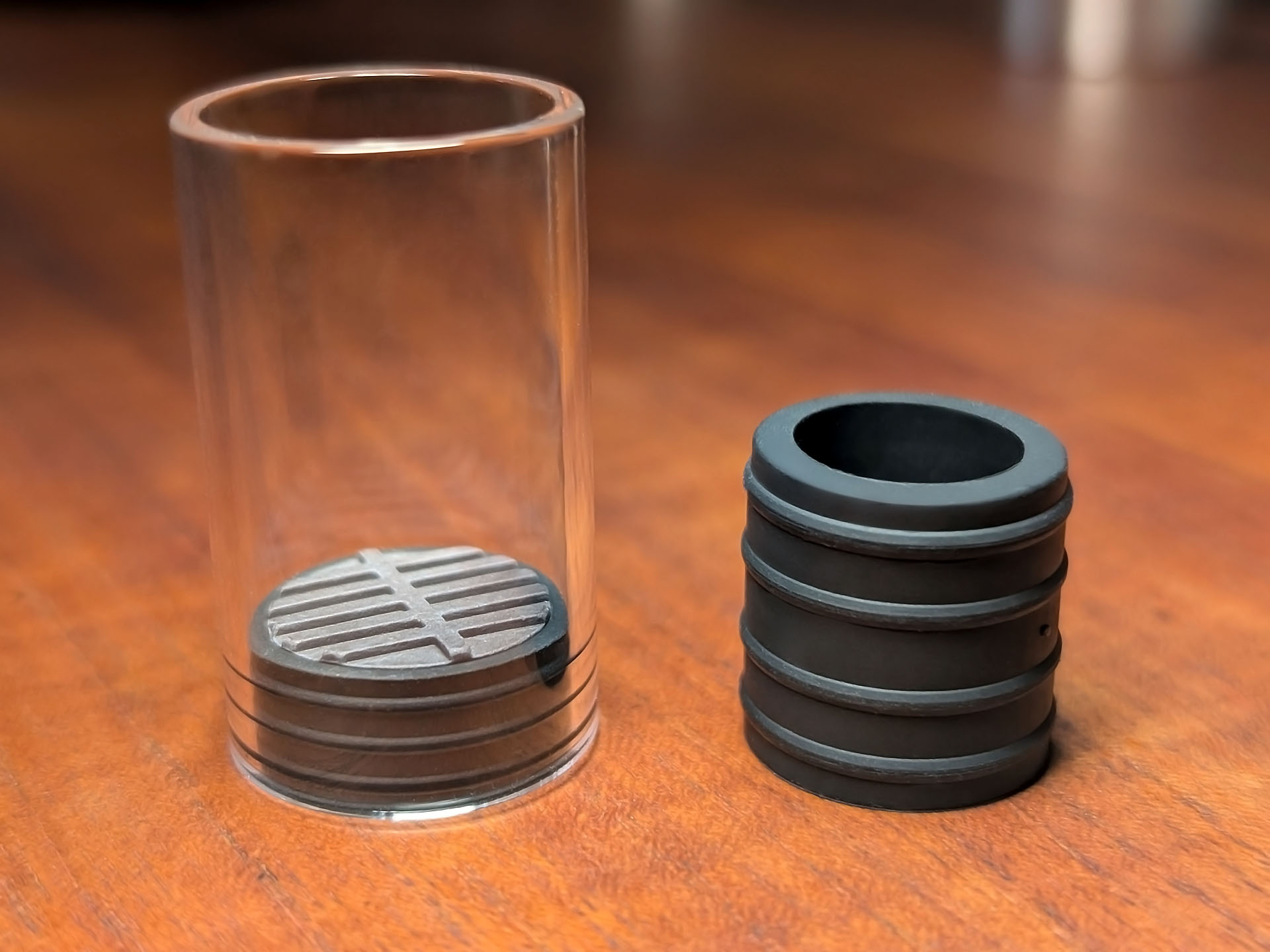Ein Glasröhrchen mit Keramik-Inlay und ein Silikon Adapter stehen auf einem Holztisch.