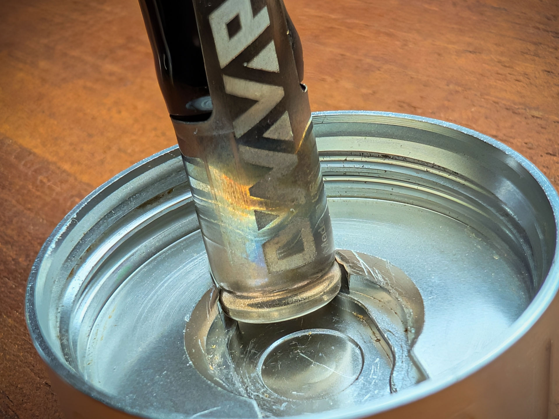 Nahaufnahme des Decappers des Mad Heaters Reload 3 liegt auf einem Holztisch. Eine Dynavap Kappe befindet sich im Decapper.