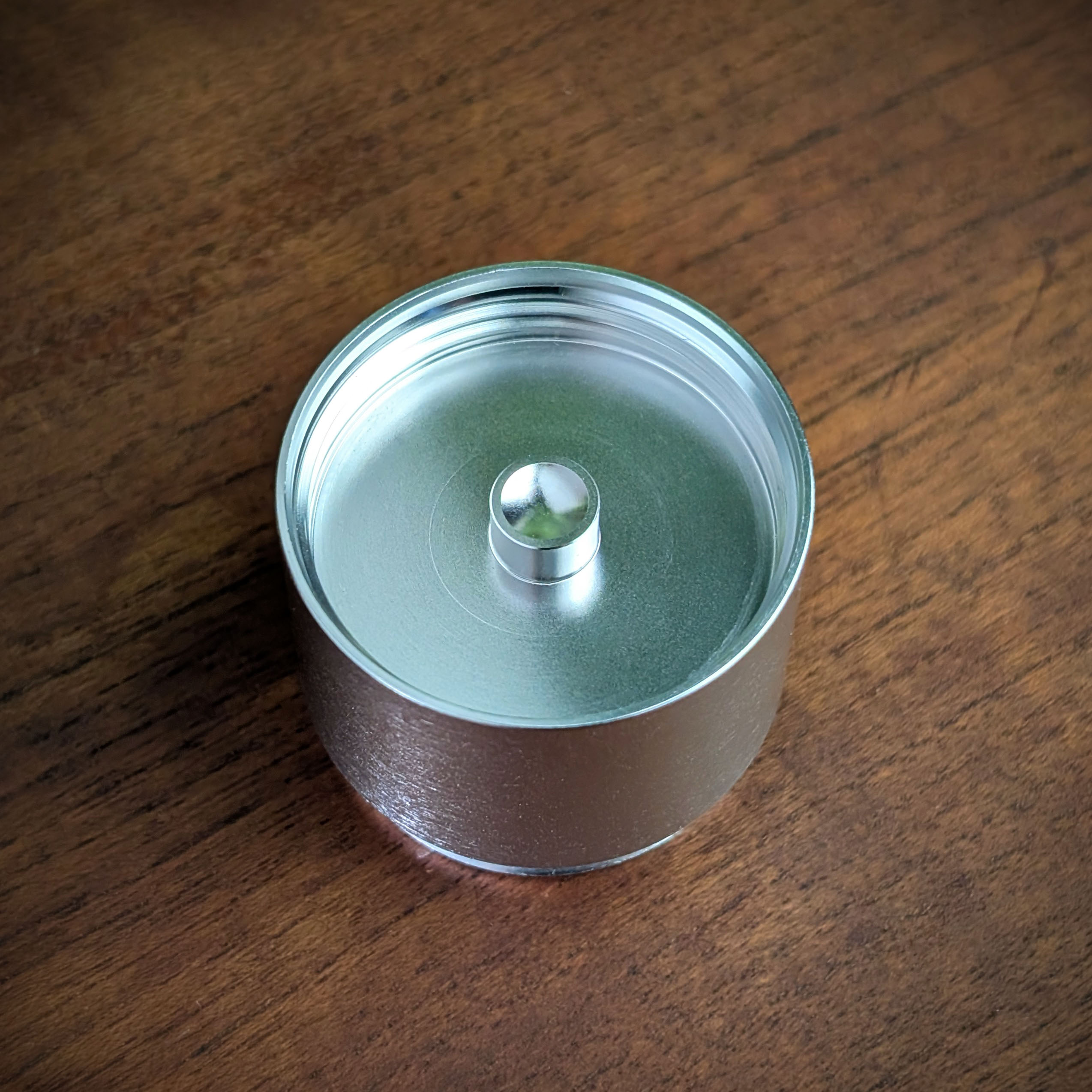 Ein Stash vom Mad Heaters Reload 3 steht mit der Unterseite nach oben auf einem Holztisch.