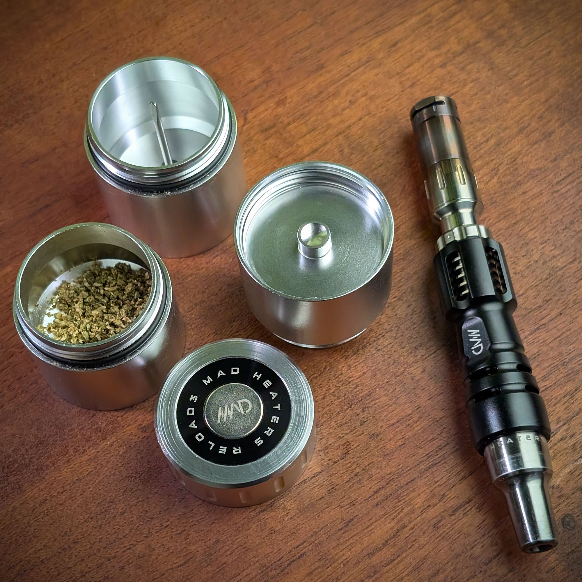 A disassembled Mad Heaters Reload 3 on a wooden table with a Tempest 2 next to it.