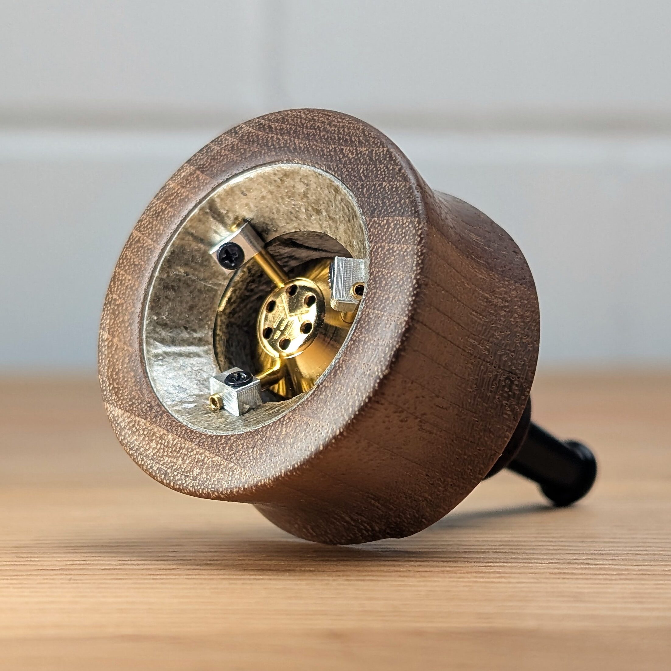 Der VapMan Vaporizer steht auf einem Holztisch. Im Hintergrund ist eine unscharfe weiße Backsteinwand zu erkennen.